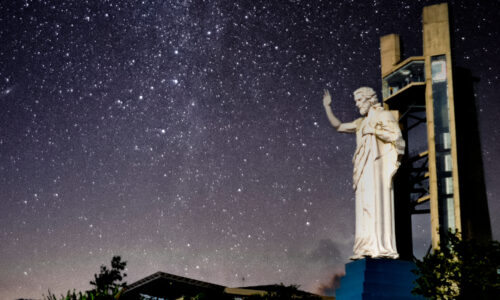 The illuminated statue of Jesus at night, standing tall on Cerro del Santisimo, radiating a sense of peace and spirituality.