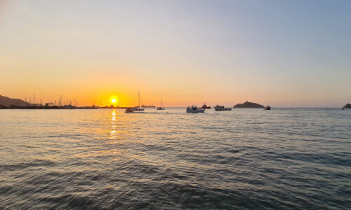 A breathtaking sunset casting a warm glow over the bay of Santa Marta, painting the sky in vibrant hues.