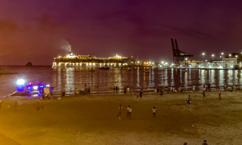 A majestic cruise liner entering Santa Marta port under a starry night sky.