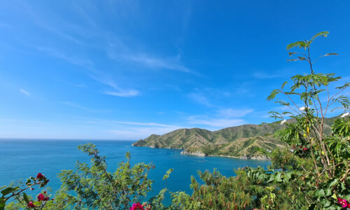 A breathtaking view of the beautiful Taganga Bay, with clear turquoise waters and lush green hills surrounding it.