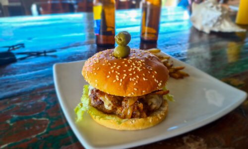 A mouthwatering hamburger paired with two ice-cold beers, the epitome of a satisfying and enjoyable life.