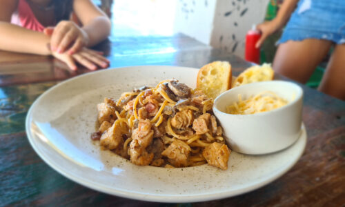 A delectable plate of chicken and bacon pasta served with garlic bread, a feast for the senses.